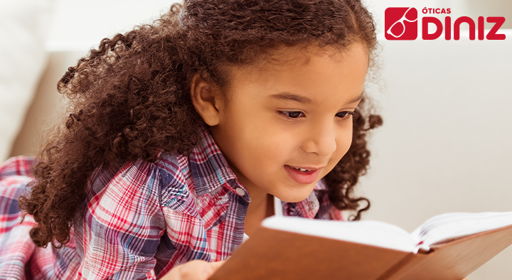 garotinha negra realizando a leitura de seu livro