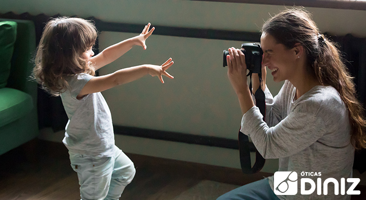 Mulher faz fotografia de uma menina usando máquina fotográfica profissional