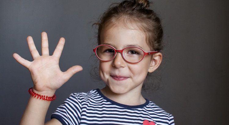 Menina de óculos vermelho com uma das mãos aberta formando o número cinco
