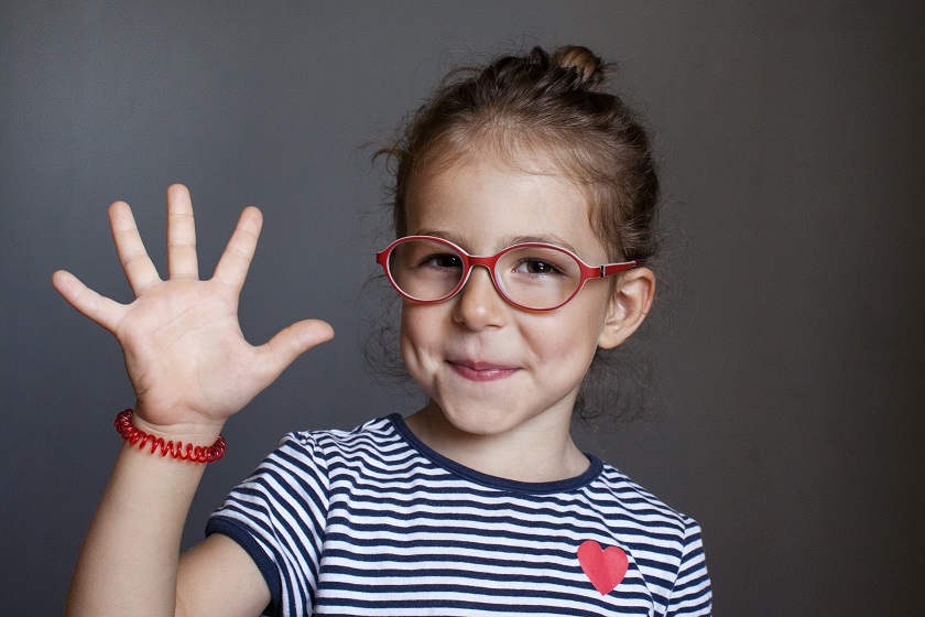 Menina de óculos vermelho com uma das mãos aberta formando o número cinco