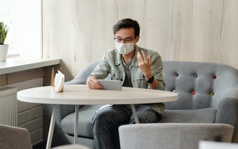 ricardo-magro-advogado-usa-mascara-e-nao-quer-embaçar-os-óculos-sentado-usando-o-celular-em-cima-da-mesa