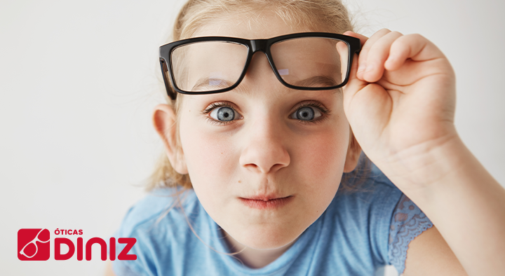Menina loira e de olhos azuis segura seus óculos.