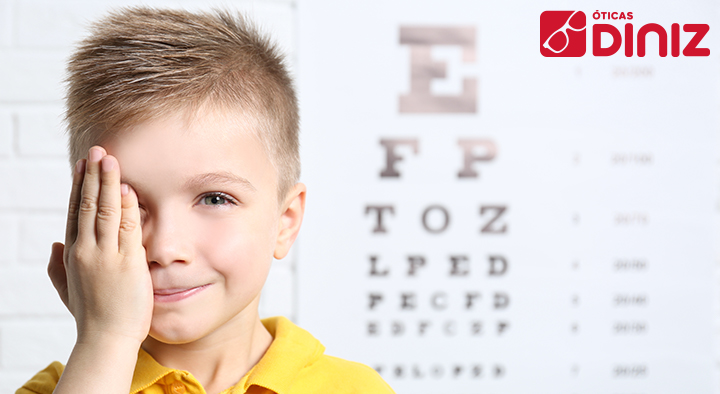 Menino tampa um dos olhos com a mão para fazer exames de vista