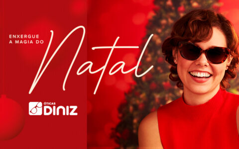 Na imagem, há uma mulher branca sorrindo de cabelo ondulado, com óculos de sol e blusa vermelha em frente há uma árvore de natal iluminada e enfeitada. A montagem tem o texto: "Enxergue a magia do Natal! Compre um óculos de sol e grane 50% desconto no segundo óculos de sol".